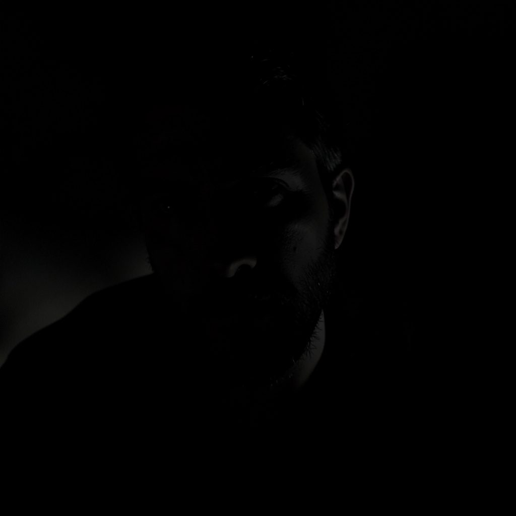 A dark atmospheric thumbnail image of a conference website, with deep black and soft grey tones.